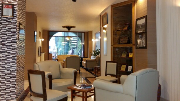 Un vestíbulo de hotel con sillones de cuero, una mesa de centro, una estantería y un área de comedor con una mesa y sillas.