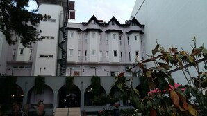 Un edificio de varios pisos con fachada simétrica, múltiples ventanas y una escalera central.