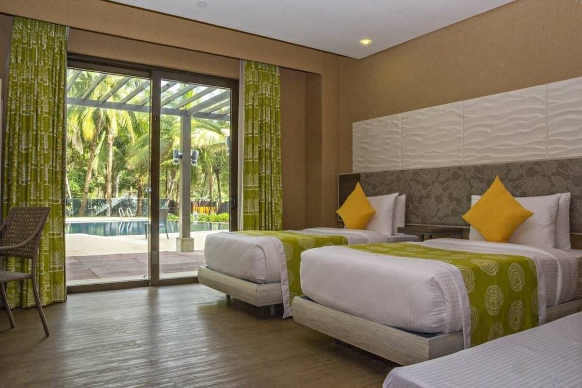 A hotel room with two beds, a chair, and a view of a swimming pool.