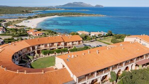 A coastal hotel with terracotta roofs, a beach, and clear blue waters. - Casa Athena (Olbia)