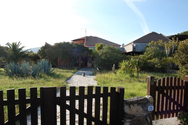 A gated entrance to a residential area with a stone pathway leading to houses.