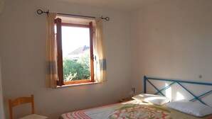 Un dormitorio con una cama individual, una silla y un ventanal con cortinas.