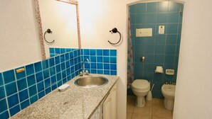 Un baño con lavamanos de granito, azulejos azules, inodoro y bidé.