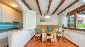 Una cocina con zona de comedor, que cuenta con una mesa de vidrio, sillas de madera y vistas al exterior por una ventana.