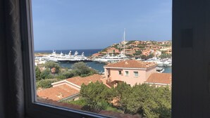 Un port de plaisance situé sur la côte, où sont amarrés des yachts, et qui est entouré de bâtiments à étages et de verdure.