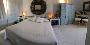 Un dormitorio con una cama grande, dos mesitas de noche con lámparas, un armario, un espejo y una silla.