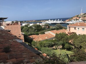 Un pueblo costero con un puerto deportivo, edificios de tejas color terracota y abundante vegetación.