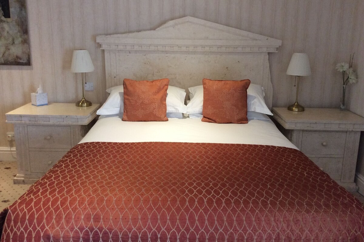 A hotel room with a bed, two nightstands, and a headboard.