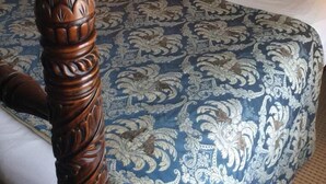 A four-poster bed with a blue and white patterned bedspread, two matching pillows, and a wooden headboard. - The Old Coach House (Blackpool)