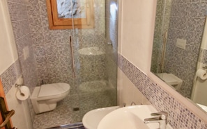 A bathroom with a toilet, sink, and mirror. - Casa Rosa (Olbia)
