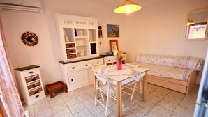 A cozy kitchen with a dining table, a sofa, and a cabinet labeled "CAFÉ ÉPICES THÉ". - Casa Rosa (Olbia)