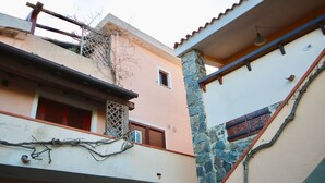 A building with a stone column, a small window, and a balcony with a metal railing. - Casa Rosa (Olbia)