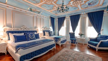 Une chambre à coucher luxueuse avec un grand lit, deux petits lits, un plafond décoré et des rideaux bleus.