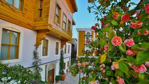 A courtyard with a wooden building, potted plants, and blooming flowers. - Seven Hills Palace & Spa (Istanbul)