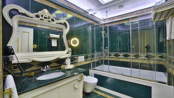 Une salle de bain luxueuse avec un grand miroir, une baignoire et une douche à parois de verre.