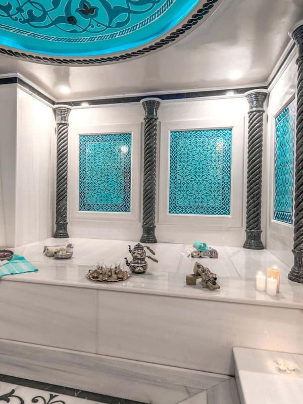 Bathroom features a large sink, decorative tile backsplash, and elegant columns.