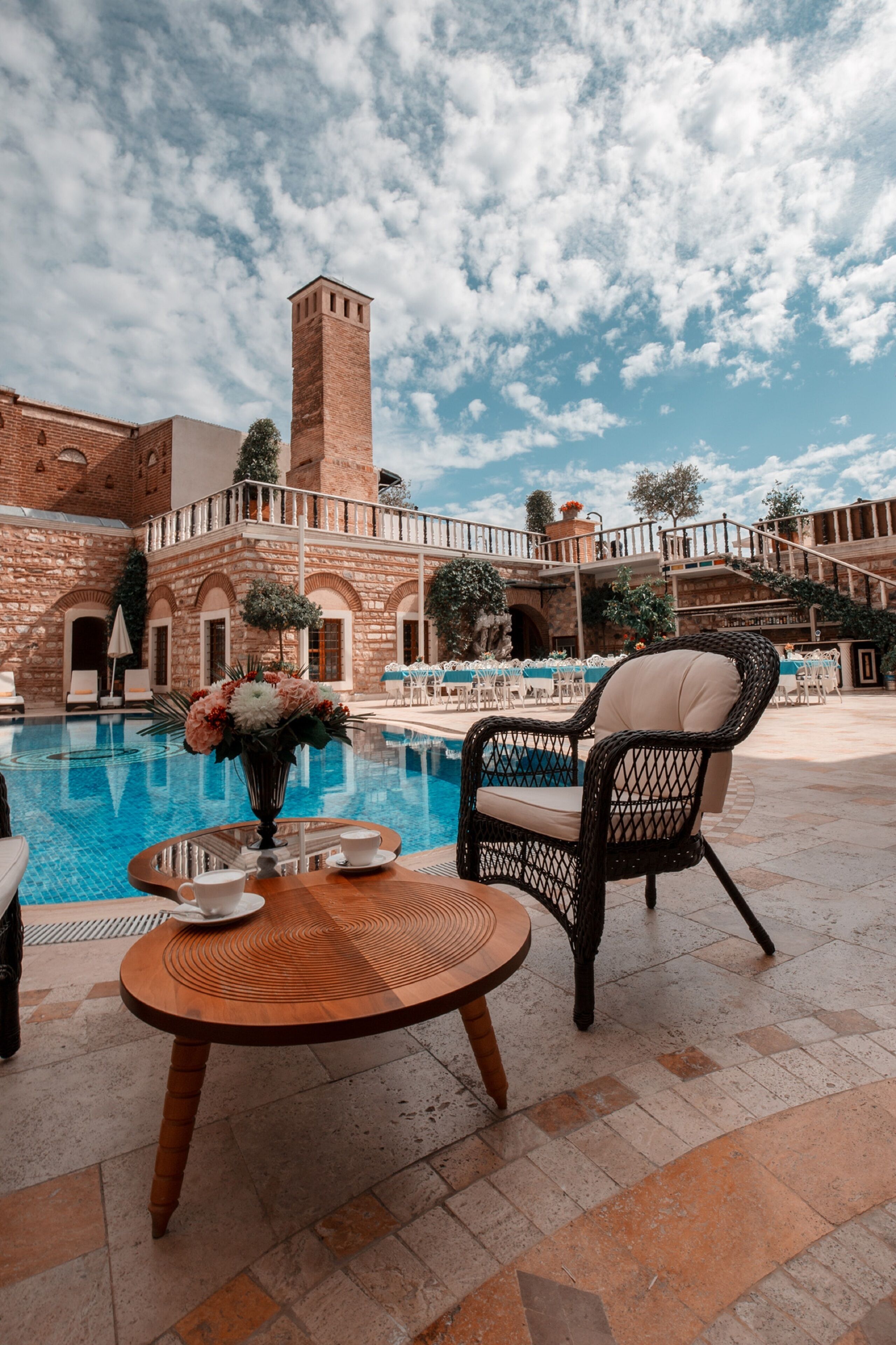 A poolside area with a brick building, a fountain, and outdoor seating.