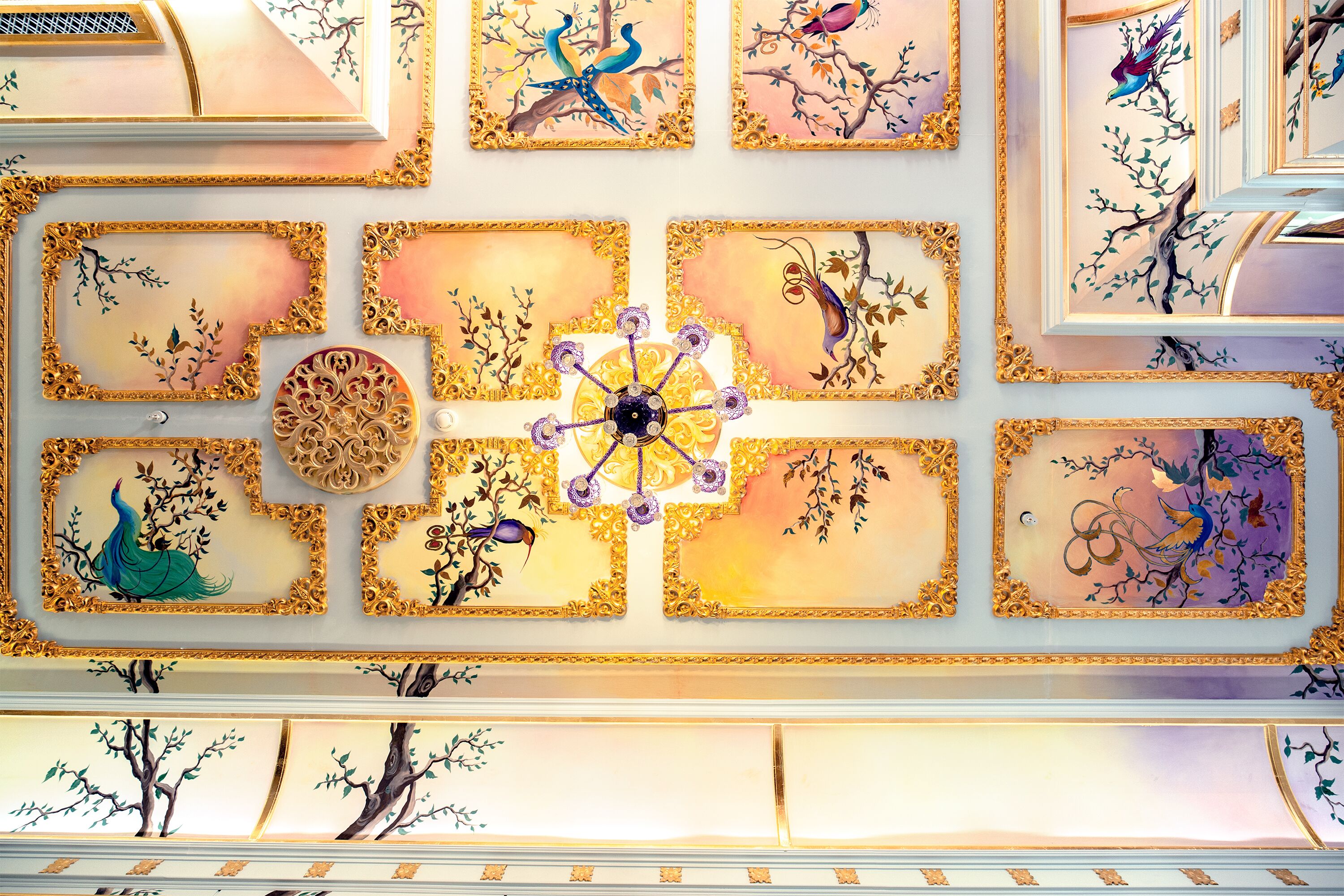 A ceiling with ornate gold frames and floral designs.