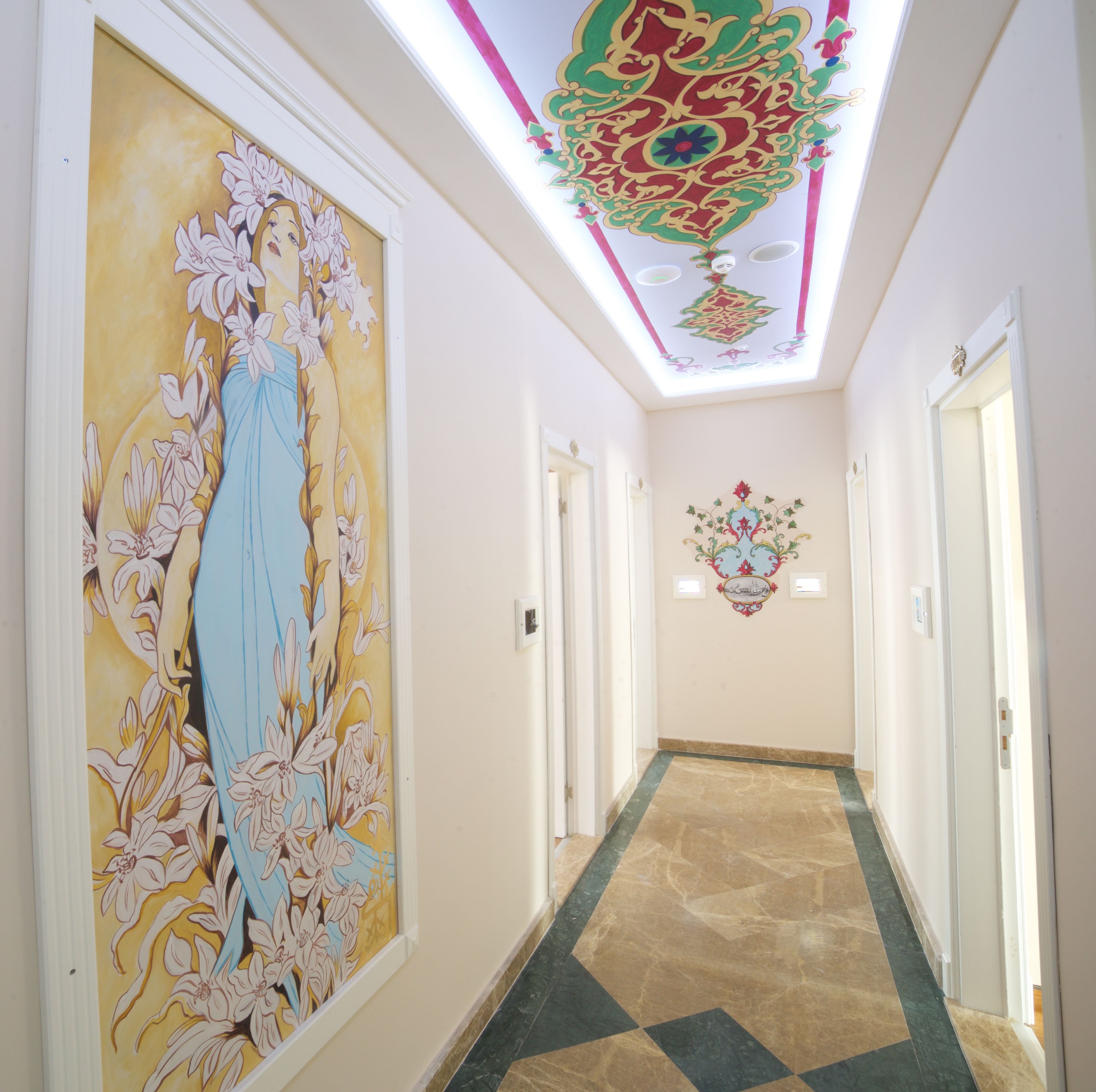 Un pasillo con un amplio mural floral a la izquierda, techo estampado y suelo de baldosas.