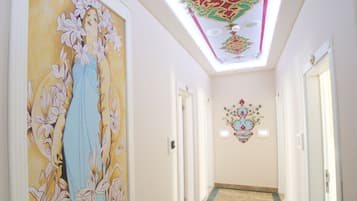 Un pasillo con un amplio mural floral a la izquierda, techo estampado y suelo de baldosas.