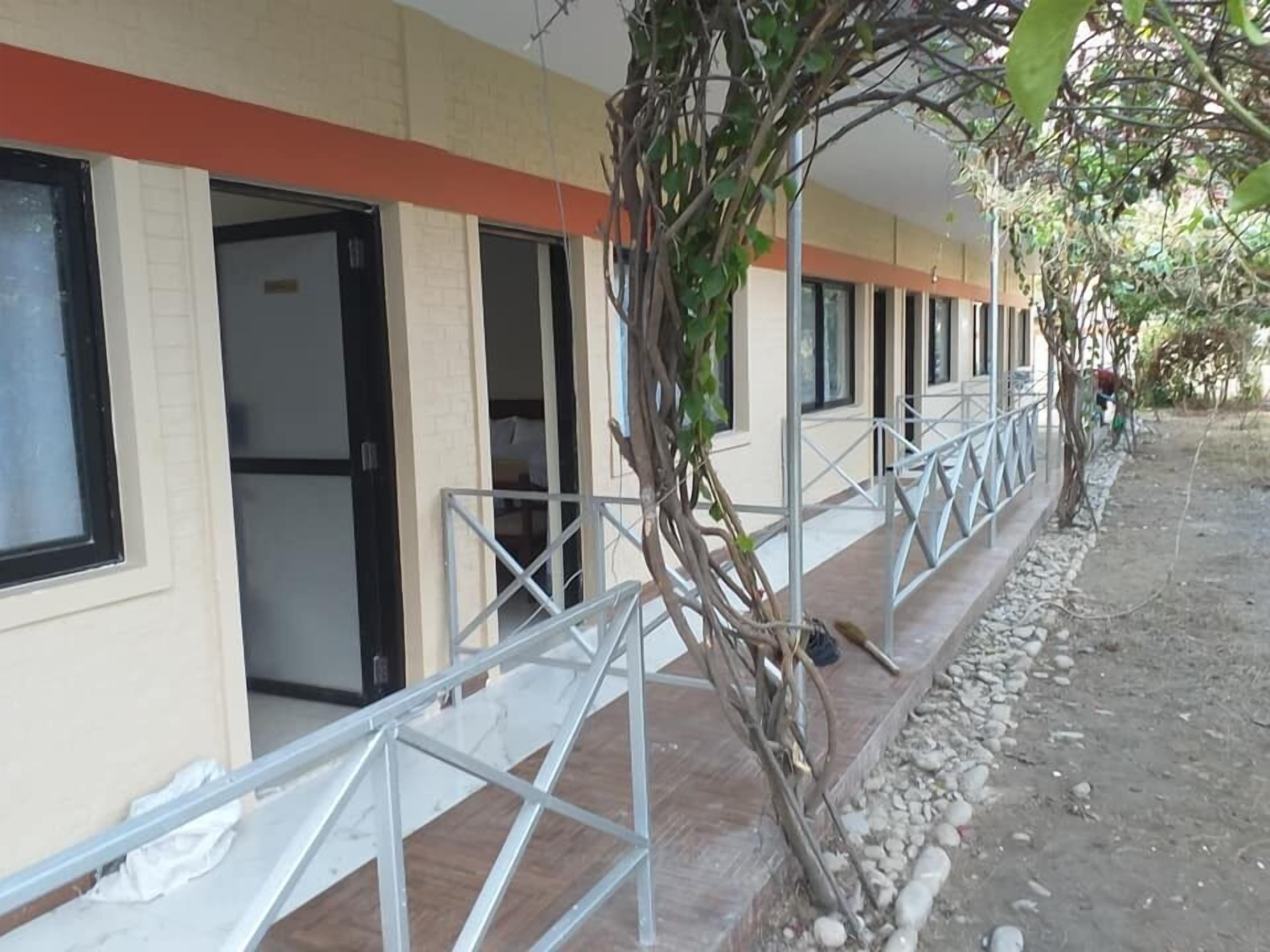 A row of hotel rooms with metal railings and a tree in the foreground.