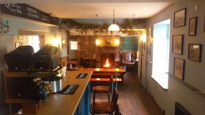 Zona de bar con parrilla, asientos y chimenea.