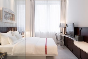 A hotel room with a bed, a TV, a desk, and a chair.