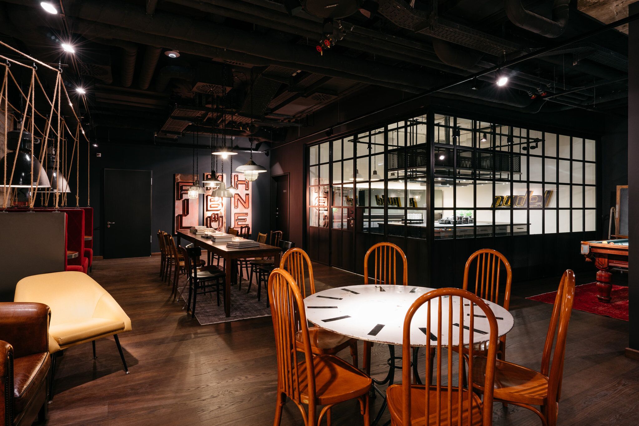 A modern dining area with a round table, wooden chairs, and pendant lighting.