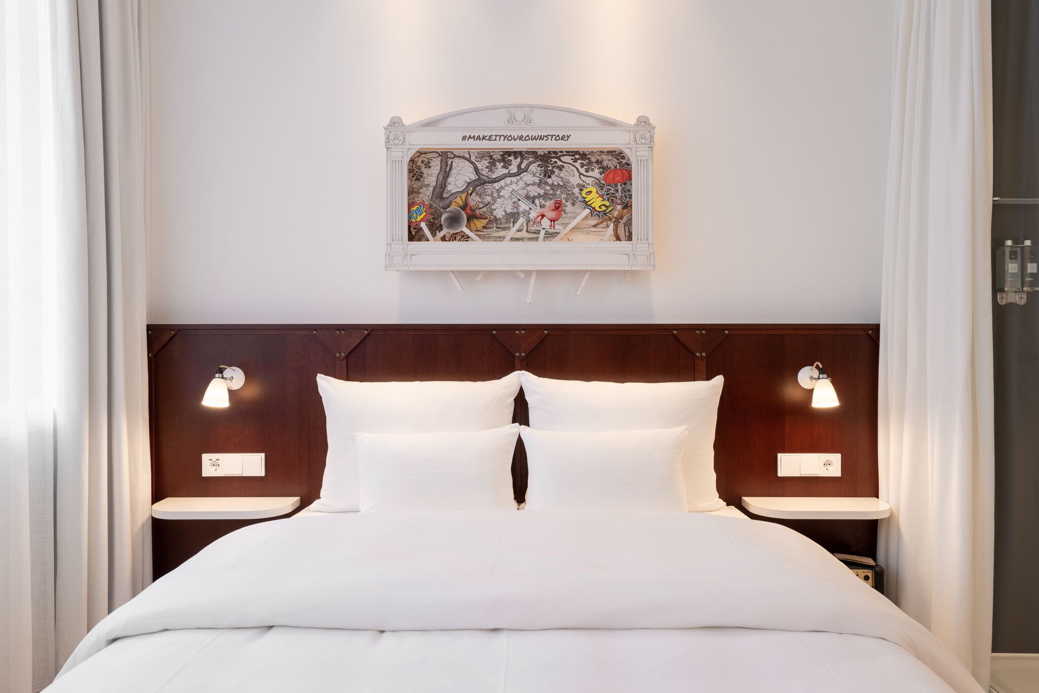 Una habitación de hotel con una cama grande, dos mesitas de noche con lámparas, un adorno en la pared sobre la cama y un cabecero moderno.