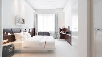 Ein modernes Hotelzimmer mit Bett, Nachttisch, Lampe und Blick auf die Stadt.