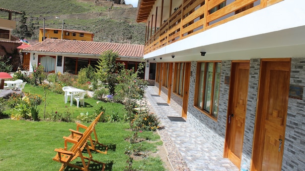 Un edificio moderno con un área exterior cubierta, un sendero de piedra y vista a una montaña.