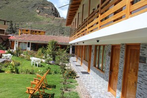 A modern building with a covered outdoor area, a stone pathway, and a view of a mountain. - Hotel Tierra Inka Sacred Valley (Ollantaytambo)