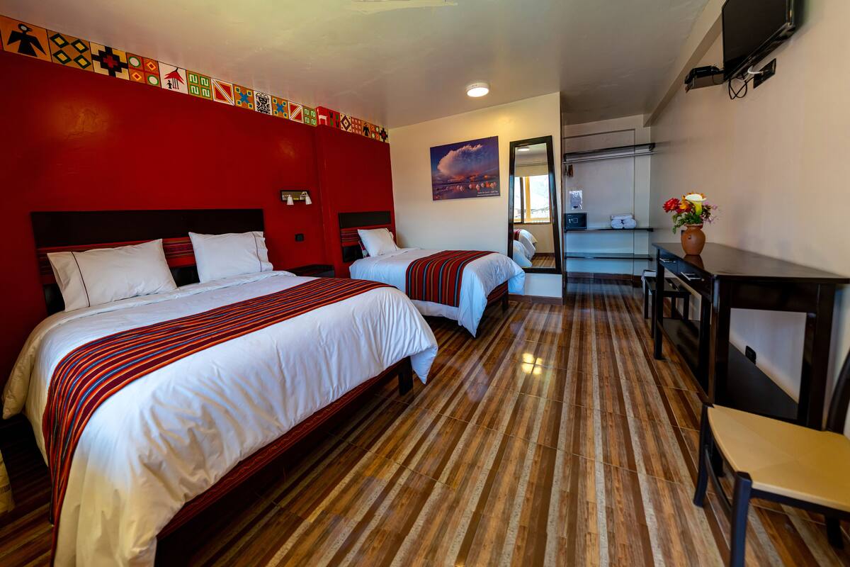 A hotel room with two beds, a desk, and a chair.
