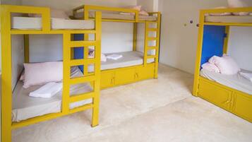 Una habitación con tres literas amarillas, cada una con colchón y almohadas.
