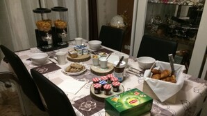 Une table à manger dressée avec divers plats et accompagnements, entourée de chaises.