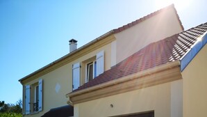 Une maison à deux étages avec un garage, une voiture garée et un ciel dégagé.