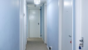 Un couloir étroit aux murs bleu clair et aux portes blanches.