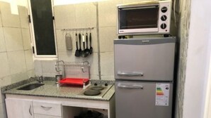 A compact kitchen with a microwave, a refrigerator, and a sink. - 1 Ambiente Avenida Cordoba (Buenos Aires)