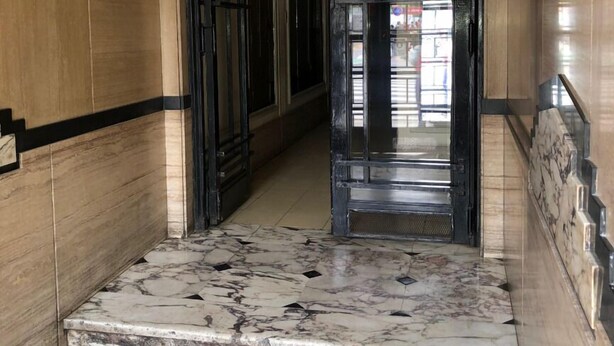 A marble staircase leading to a door with a security camera above it. - 1 Ambiente Avenida Cordoba (Buenos Aires)