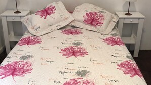 A bed with floral bedding and pillows, two bedside tables with lamps, and a white wall. - 1 Ambiente Avenida Cordoba (Buenos Aires)