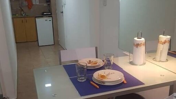 A dining area with a table set for two, a microwave, and a small refrigerator in the background. - 1 Ambiente en Recoleta (Buenos Aires)