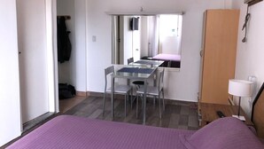 A bedroom with a bed, a desk with chairs, a wardrobe, and a mirror. - 1 Ambiente en Recoleta (Buenos Aires)