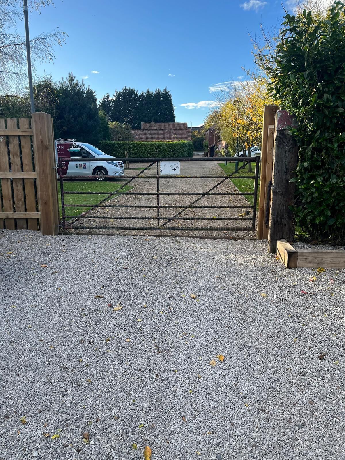 A gated driveway leading to a building with a parked car.