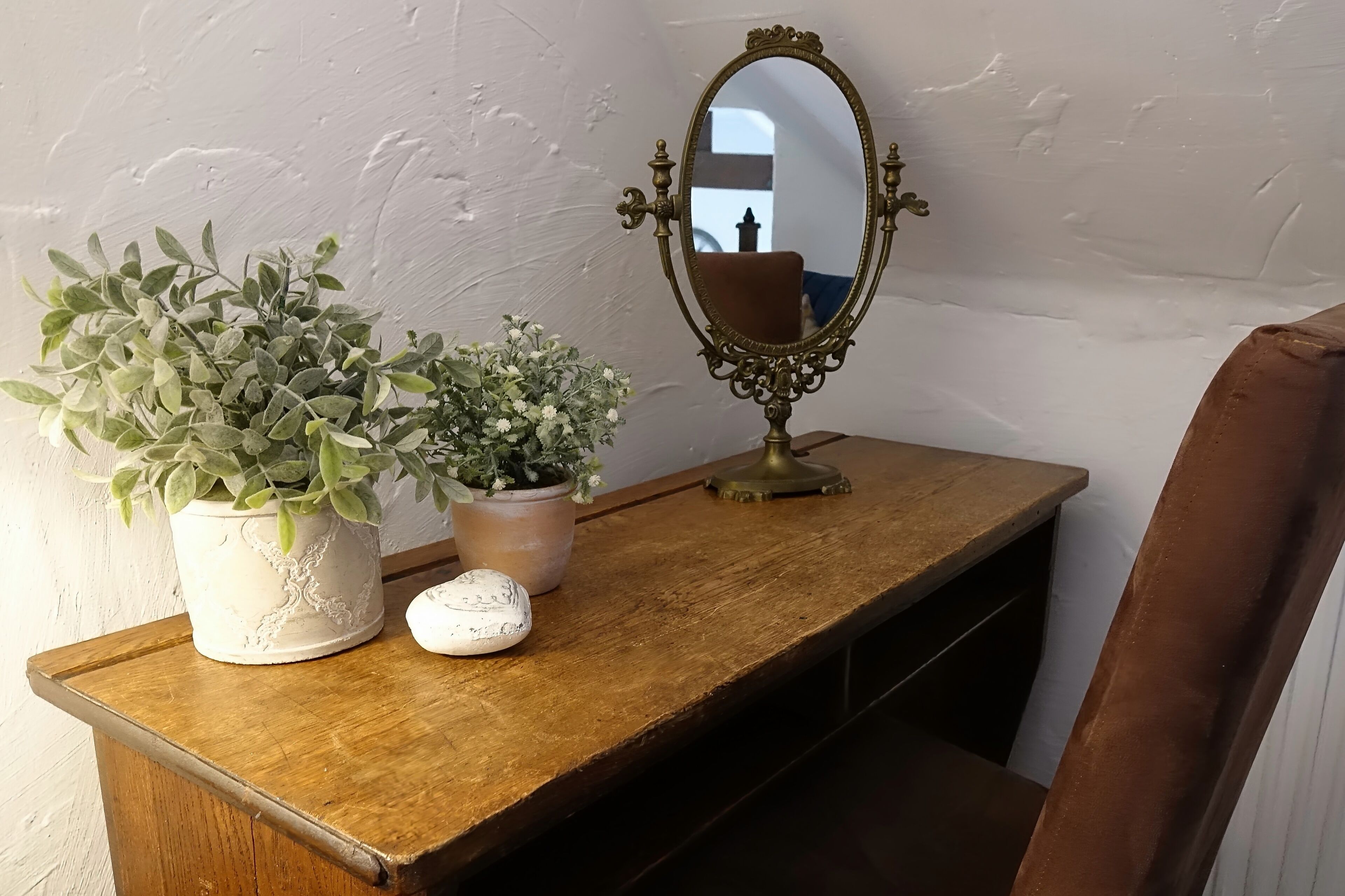 A wooden table with two potted plants and a decorative mirror.