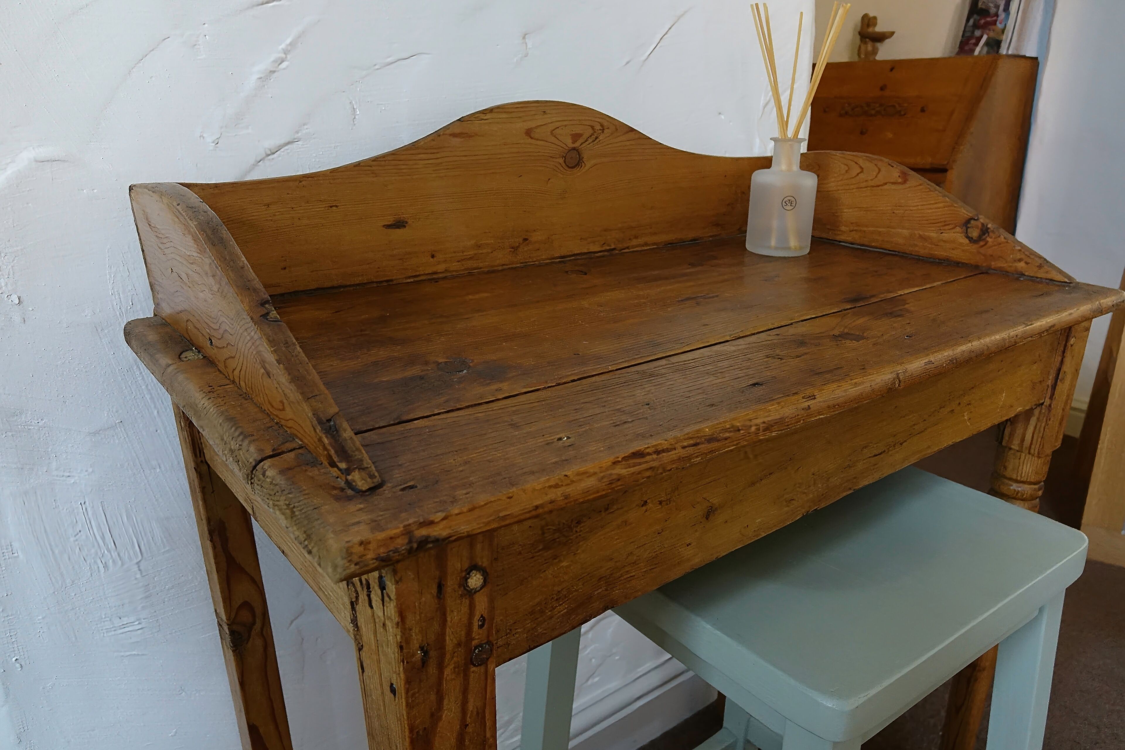 A wooden bench with a light blue stool in front.