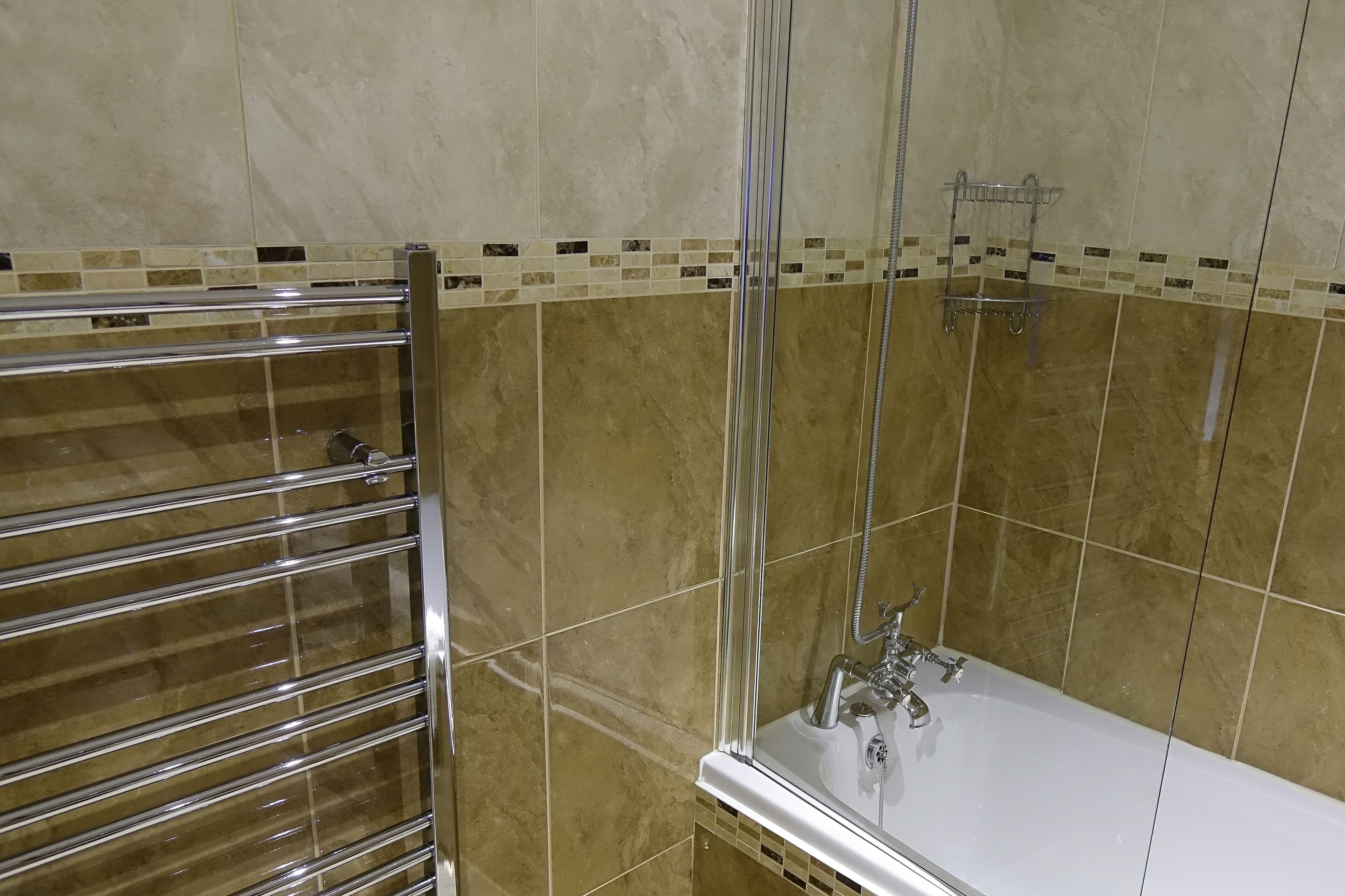 Un baño con ducha envuelta en vidrio, una bañera blanca y un perchero de cromo.