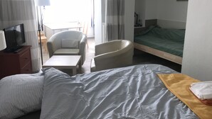 Hotellihuone, jossa on sänky, tuoli, työpöytä ja televisio.