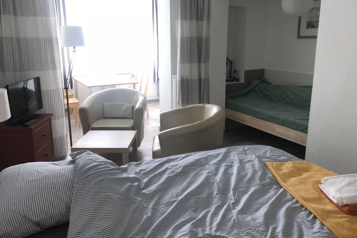 A hotel room with a bed, a chair, a desk, and a television.