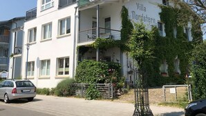 Valkoinen rakennus, jossa on parvekkeita ja kyltti, jossa lukee: ”Villa Nordstern”.