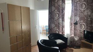 Hotellihuone, jossa on sänky, vaatekaappi, työpöytä, tuoli ja televisio.
